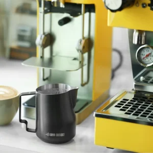 crna latijera za mleko bomber pored aparata za espresso